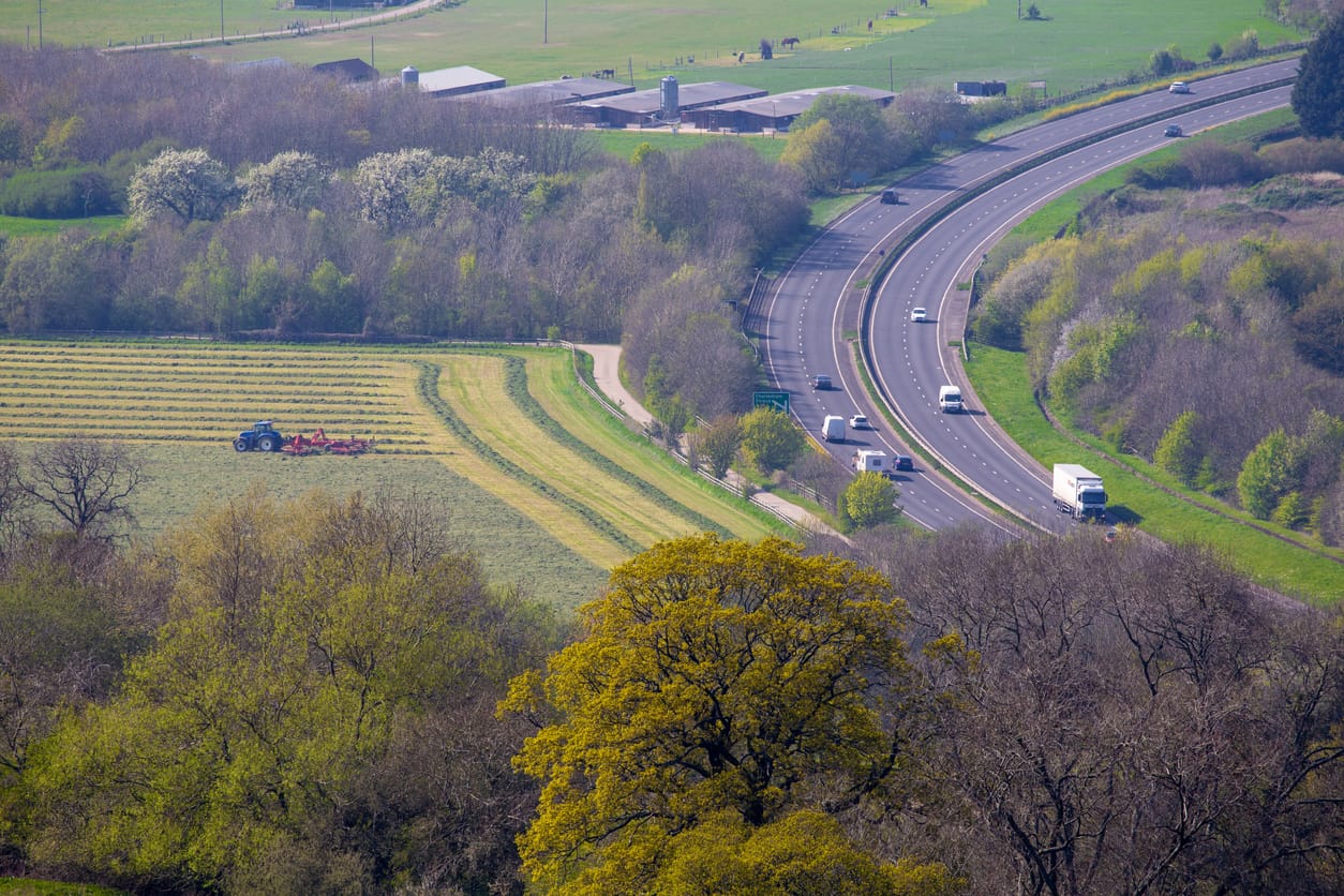 Elevated view of a dual carriageway slicing through the Cotswold landscape - highlighting the environmental problems with traffic pollution and road infrastructure Elevated view of a dual carriageway slicing through the Cotswold landscape - highlighting the environmental problems with traffic pollution and road infrastructure